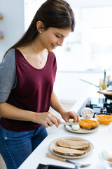 Beautiful woman preparing toast with mashed vegetables and hard-boiled eggs.