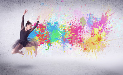 Modern street dancer jumping with colorful paint splashes