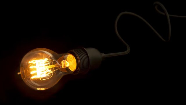 Symbolic bulb. Carbon light bulb in vintage style with a winding cord flickering.