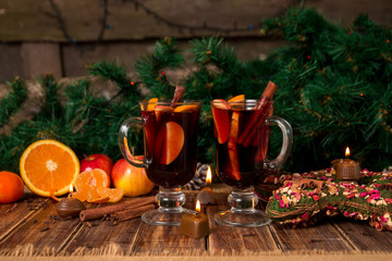 Christmas mulled wine with fruits and spices on wooden table. Xmas decorations in background. Two...