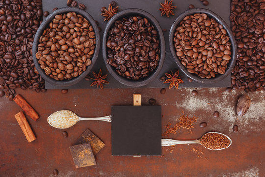 Roasted coffee beans, dark chocolate, spices and blank tag on a rustic background © happyimages