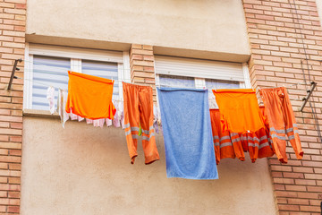 Clothes of a worker hanging from a clothesline to dry - Powered by Adobe
