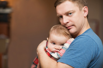 The father holds on hands of the little sad baby. Family concept. At the baby teeth are cut.

