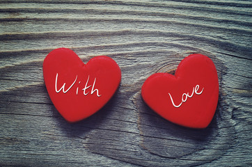 Red hearts and the text "With love ".Two red hearts on a wooden old background. Romantic card. A declaration of love in vintage style. A gift by St. Valentine's Day. Two red heart plasticine
