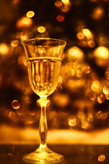 festive atmosphere in the evening with a glass of champagne and  bokeh. Christmas, New Year's atmosphere. golden color, soft focus, monotony.
