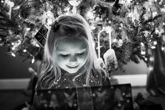 young girl opening magical present under the christmas tree