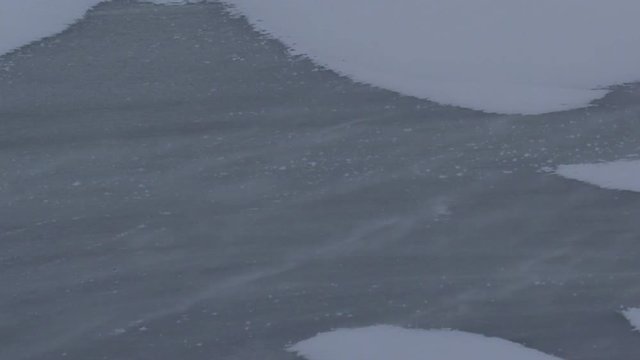 Slow motion - gritty snow blowing over slick ice