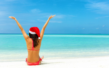 Attraktive Frau im Bikni und Weihnachtsmütze freut sich am tropischen Strand