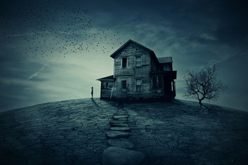 Home Return. Young man stand at the corner of a ravaged house, looking far away for someone. A...