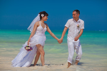 Bride and groom running on the beach