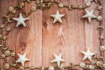 golden   christmas frame with a golden  chain and white stars   on  wooden table 
