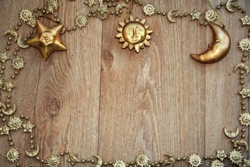 golden   christmas frame with a golden  chain and golden sun, moon and star    on  wooden table 