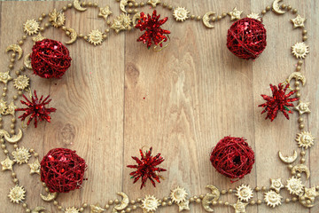 golden   and red christmas frame with a golden  chain and red balls  on  wooden table 