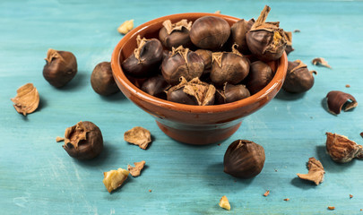 Roasted chestnuts in earthenware bowl on turquoise