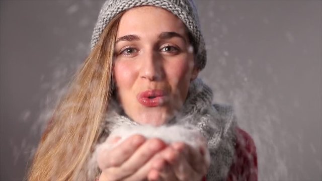 beautiful young woman blowing snow to celebrate a joyful winter