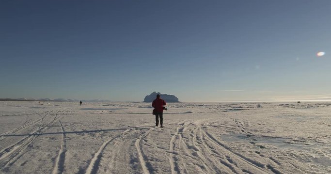 Photographer walks across sea ice on sunny day
