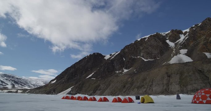 Clouds pass over mountain above line of expedition tents on sea ice