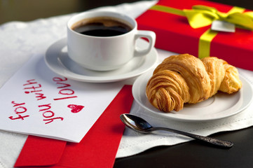 A cup of coffee and a croissant. Festive breakfast Valentine's Day with love letters.