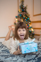 ridiculous funny child with gift  in front of a Christmas tree,