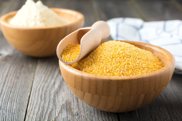 Raw corn grits polenta in a bamboo bowl on the old wooden background. Selective focus