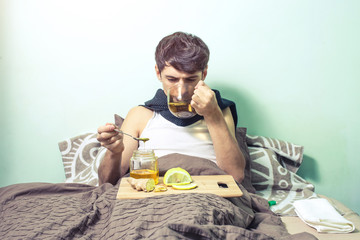 young man lies in bed sick with colds and flu