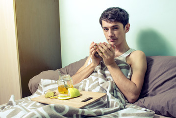 young man lies in bed sick with colds and flu
