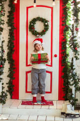 funny girl child gnome in santa hat with gift on  porch of house