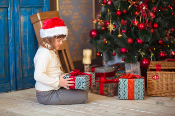 Fototapeta na wymiar child girl with a gift near Christmas tree, blue room,