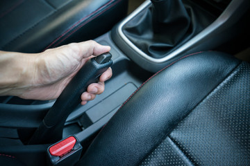 Hand pulling the hand brake in car - car interior, Focus on hand break