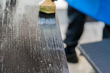 Close up paintbrush in hand and painting on the wooden table. 
