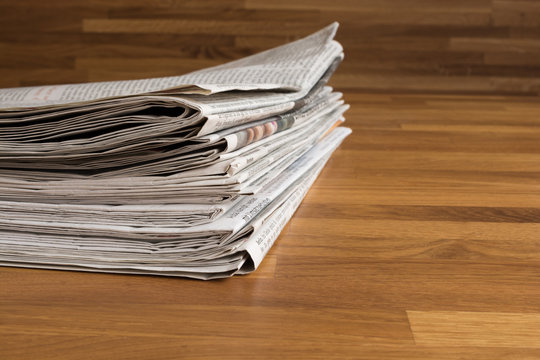 Ein Stapel Zeitungen auf einem Holztisch