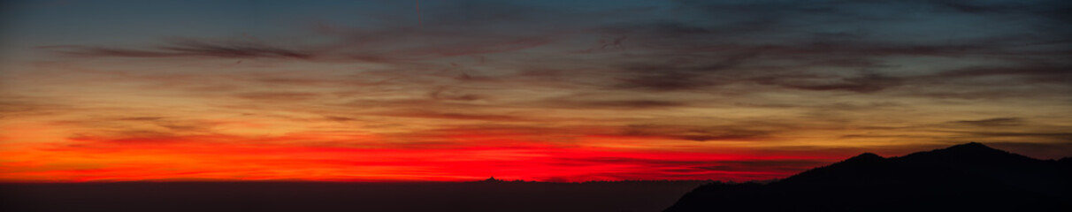 Fiery sunset from mountain pick with thin glazes in the sky evening. Fall season. Orobie alps.