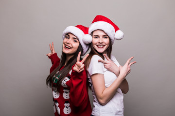 Two girls in Santa hat isolated on grey background