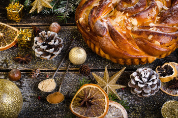 Christmas background - cake, stars, dry oranges, anise, cane, cinnamon on dark wood.