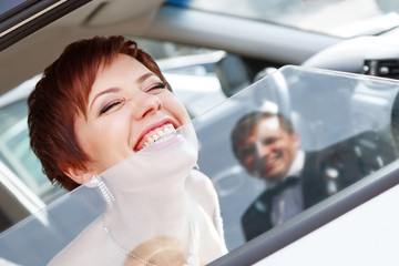 Red-haired funny bride in the car smiling groom. Woman 35 years. Wedding.