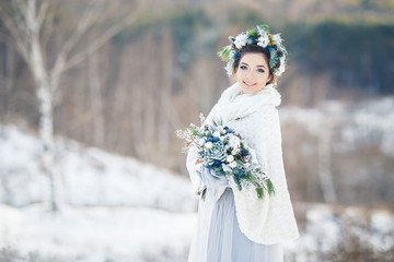 Bride with bouquet looking at the camera. Bride in the Park in winter.