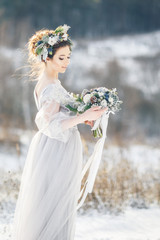 Beautiful bride admiring wedding bouquet. Winter wedding. Winter wedding bouquet.