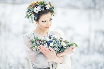 Portrait of a beautiful bride with a bouquet. Wedding ceremony in winter.