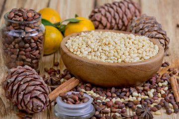Cedar nuts in wooden bowl. Cones, tangerines and rolls cinnamon on a wooden table