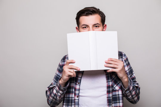 Young Man In Suit Cover Face With Book Over White Background