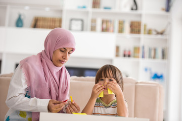 Arabic mother with little son learning in living room