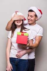 Pretty couple with christmas surprise on grey background