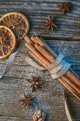 cinnamon sticks with ribbon, spices and walnuts on wooden table, wishing merry christmas