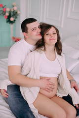 Family waiting for baby's birth. A pregnant woman and her husband wearing white clothing