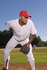 Young baseball pitcher playing on field with team mate in the background
