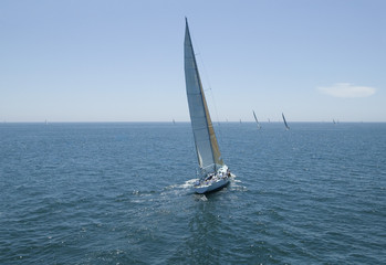 Obraz premium Overview of sailboats racing in the blue and calm ocean against sky