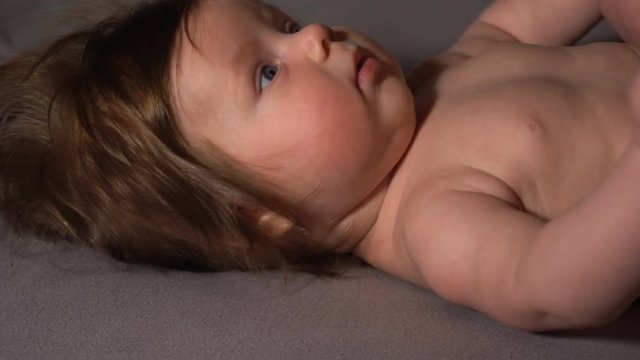 Cute little girl lying on bed and looking in camera