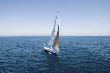 Obraz premium Sailboat at the peaceful blue ocean against the sky