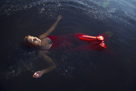 Finland, Pirkanmaa, Tampere, Pyhajarvi, Woman in red dress floating on water