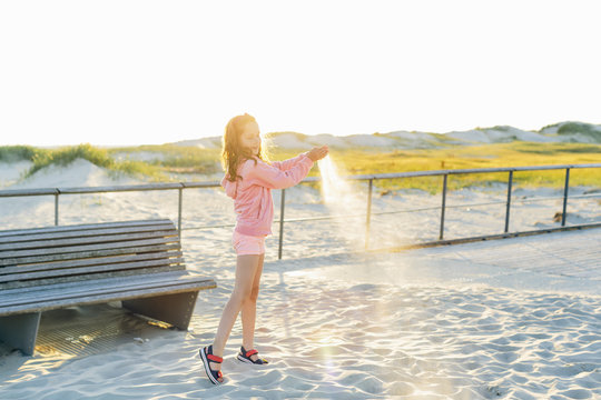Germany, Schleswig-Holstein, Kreis Nordfriesland, Sankt Peter-Ording, Girl (10-11) pouring sand on beach